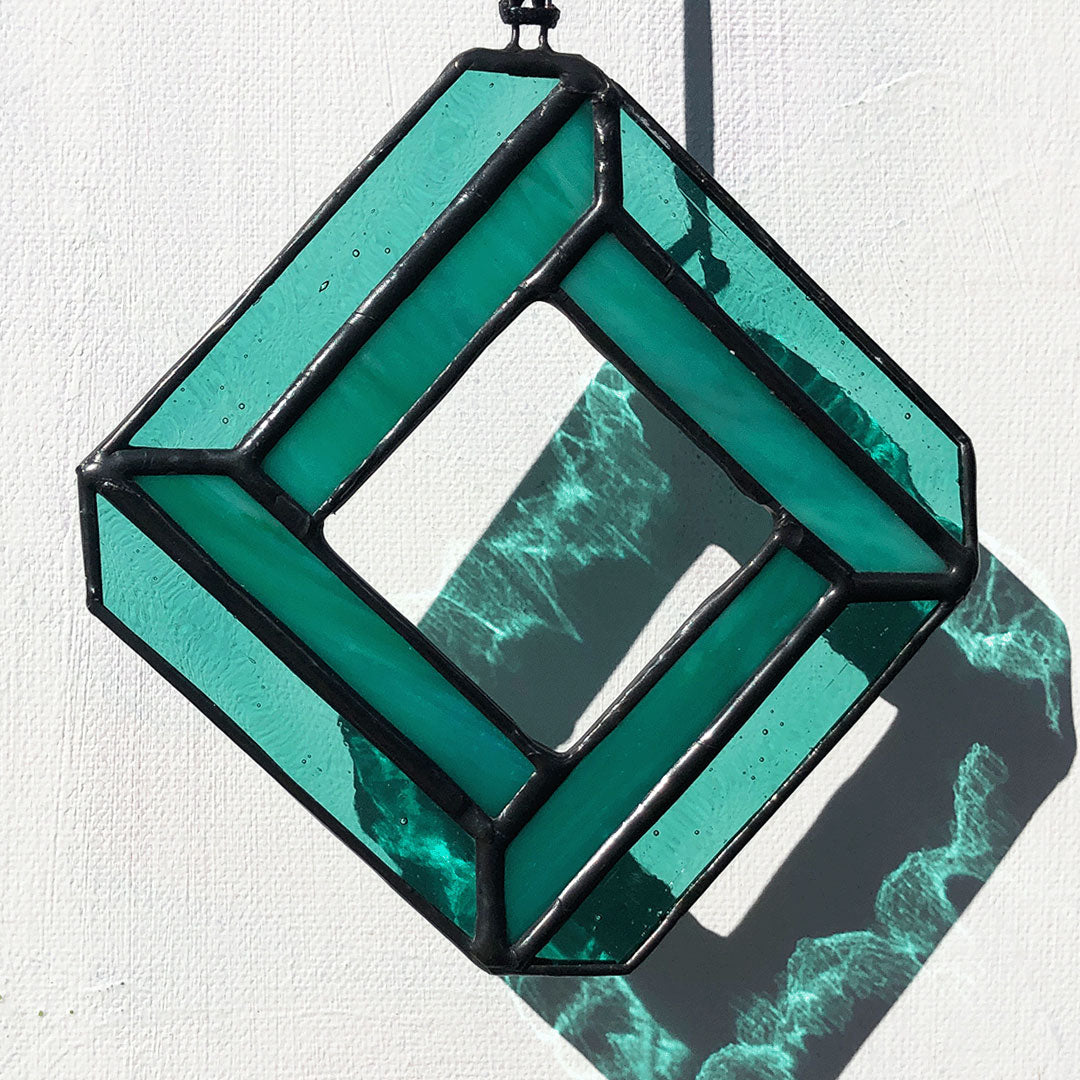 image of teal geometric diamond glass suncatcher on white background showing teal coloured glass refractions